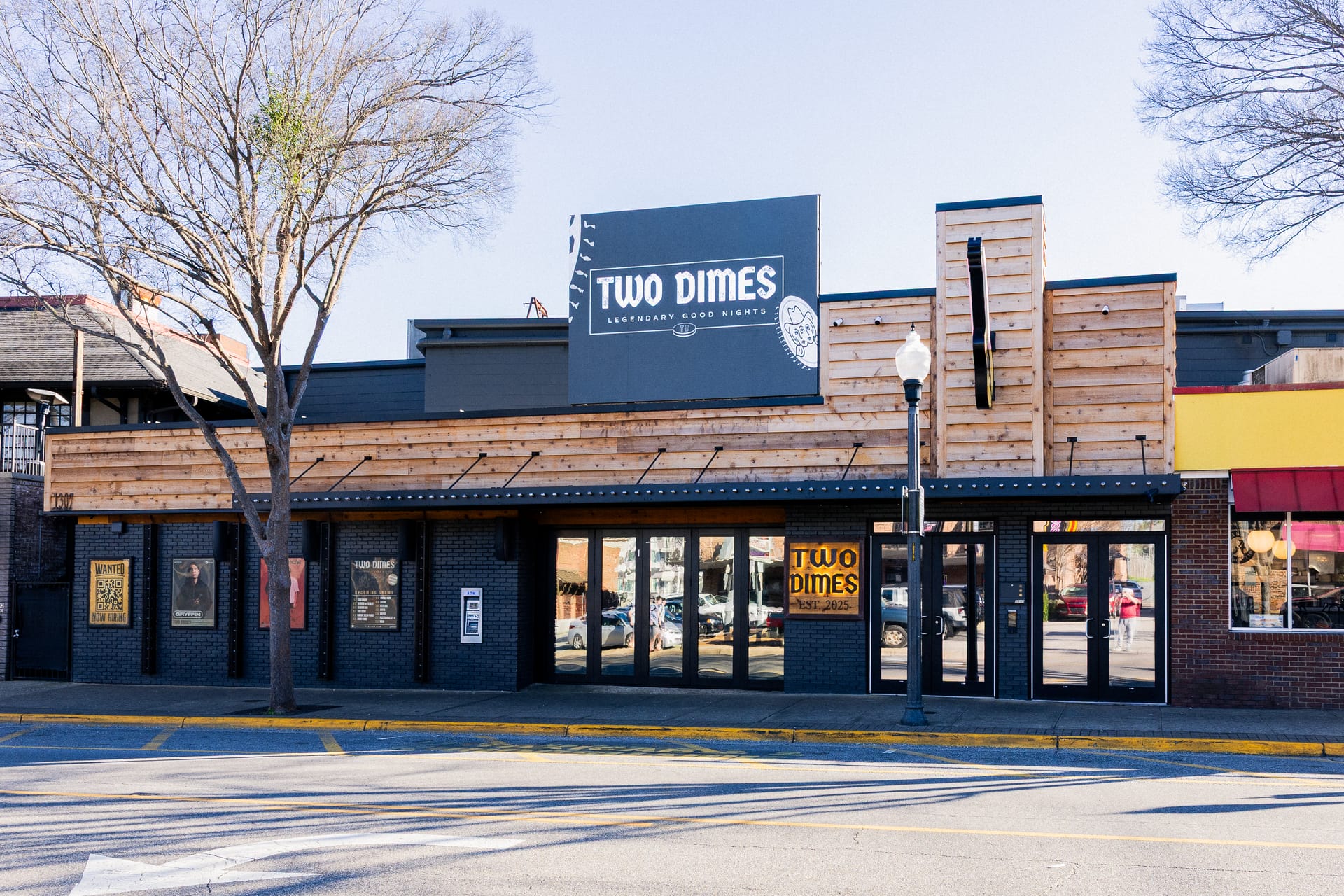 Completed Two Dimes façade with timber cladding, black brickwork, glazed entrances and the venue sign