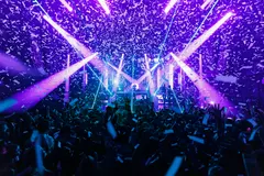 Wide view of an event at Two Dimes with stage lighting and confetti above the audience