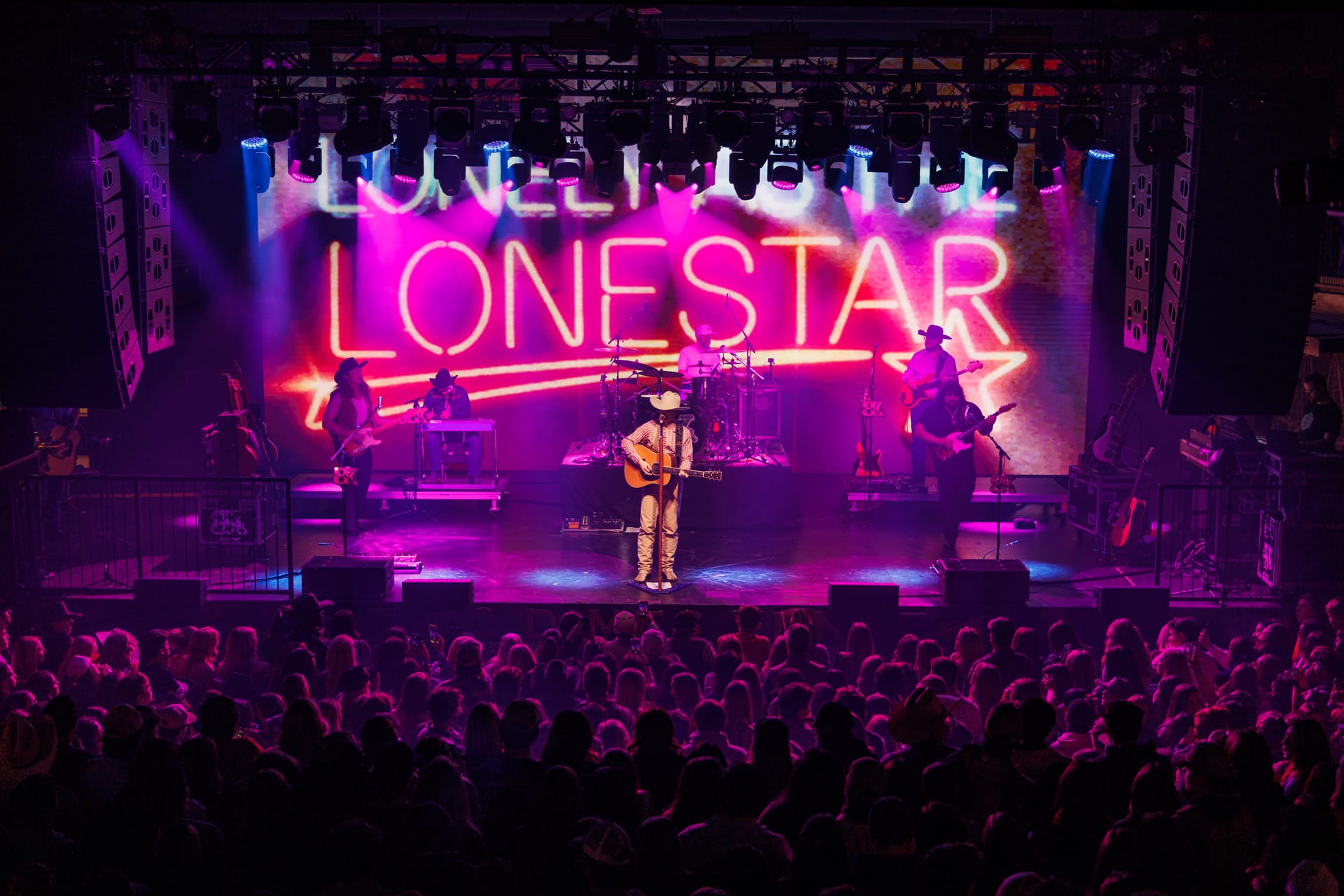 Wide view of the completed Two Dimes stage, speakers and lighting above an audience during live music