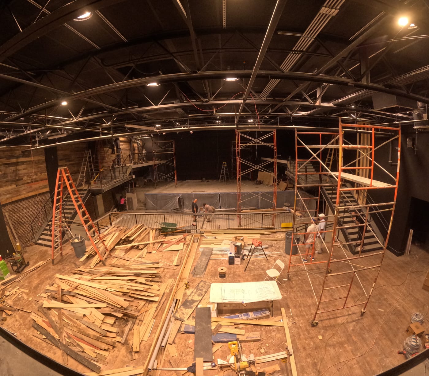 Two Dimes interior under construction, with scaffolding, ladders and stacked lumber in front of the stage platform